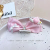 Pink bow hair accessory for children with white feathers and rhinestone pearl accents