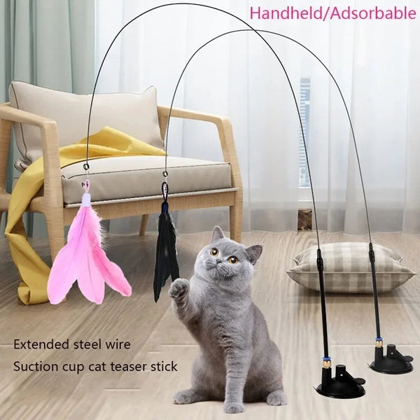 A gray cat is interacting with a handheld adsorcable suction cup cat teaser stick featuring a pink feather toy.