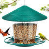 Grüner wasserdichter Vogel-Futtermittelspender mit konischer Dachform, gefüllt mit Samen, hängend an einem Draht.