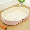 A pink washable waterproof dog bed mat with a light beige interior is shown on a wooden surface.