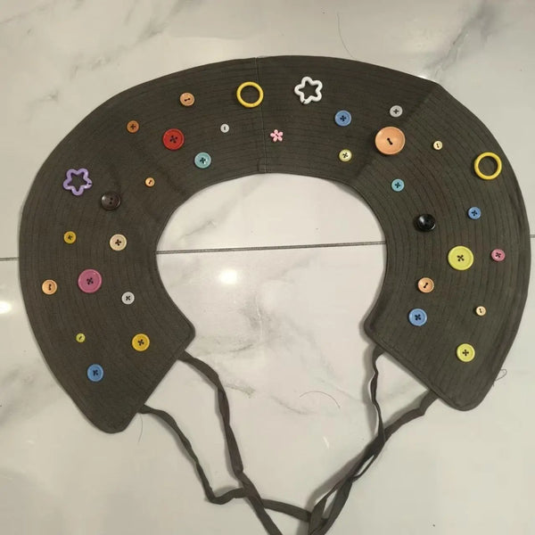 A dark gray silicone collar for pets featuring various colored, star-shaped and round plastic embellishments.