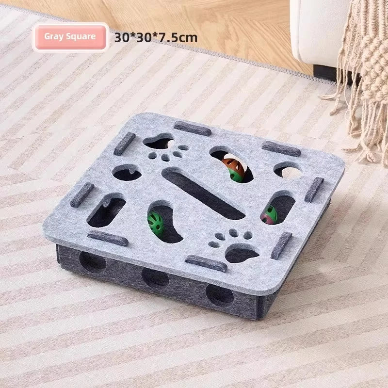 A gray square interactive cat puzzle toy with various holes and slots for indoor play