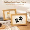A wooden photo frame displaying a black paw print on a white background, set on a wooden surface.