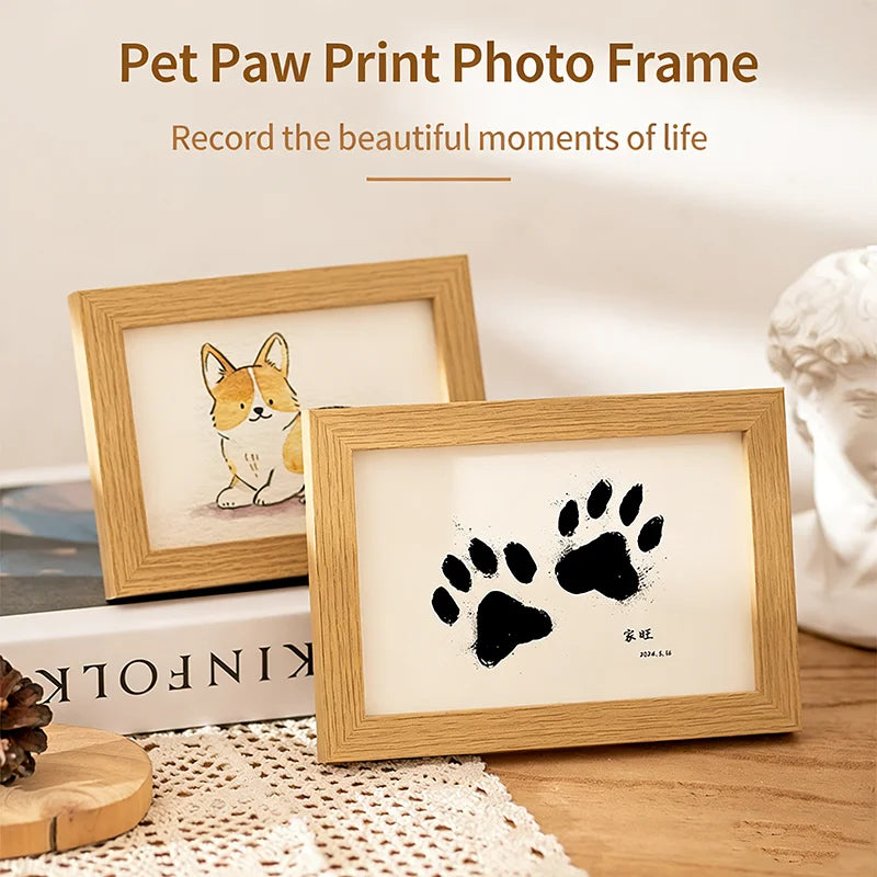 A wooden photo frame displaying a black paw print on a white background, set on a wooden surface.