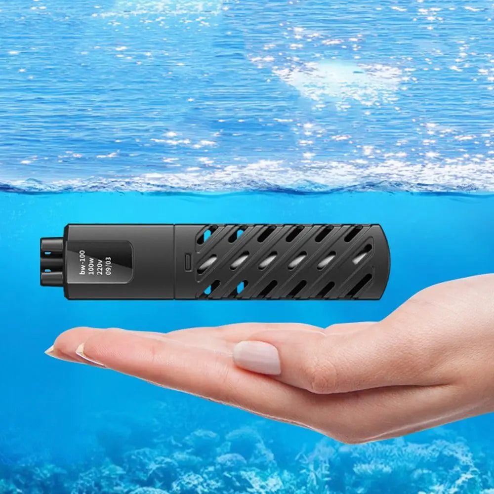 A hand holds a black submersible heater with a textured surface underwater.