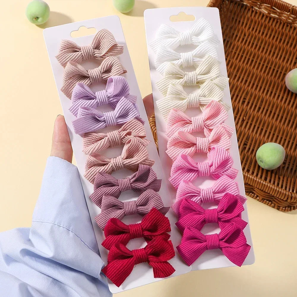 Collection de nœuds papillons pour cheveux roses et violets dans un emballage plastique sur fond clair.