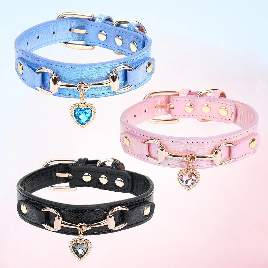 Three dog collars in blue, pink, and black leather with gold hardware and heart-shaped rhinestone charms.