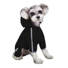 A small, light-colored dog wearing a black waterproof raincoat with a hood and reflective features.