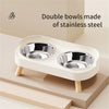 A white stainless steel double bowl for pets is shown on a light wooden surface.