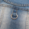 Close-up of a blue denim dog jacket showing a D-ring leash attachment on the pocket