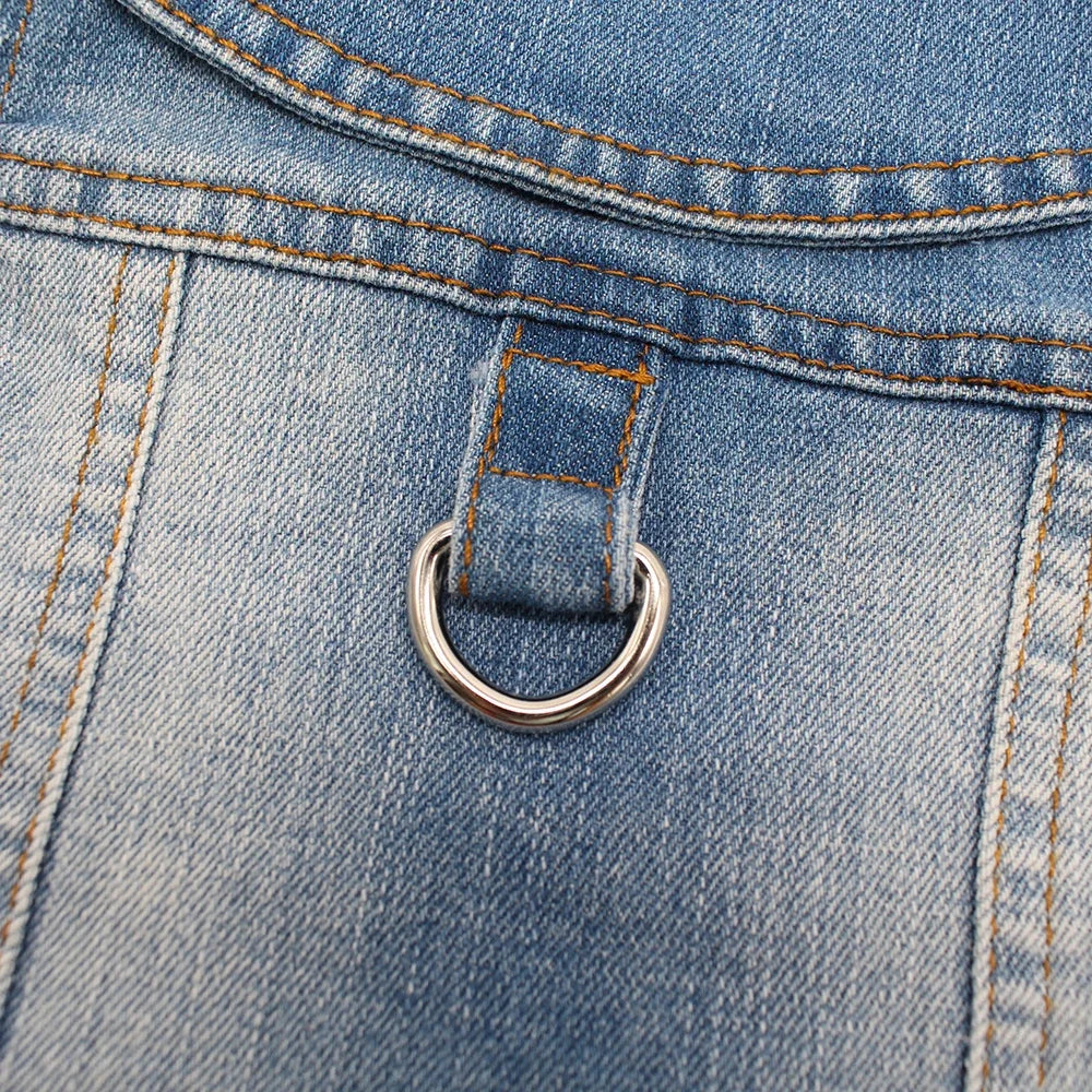 Close-up of a blue denim dog jacket showing a D-ring leash attachment on the pocket