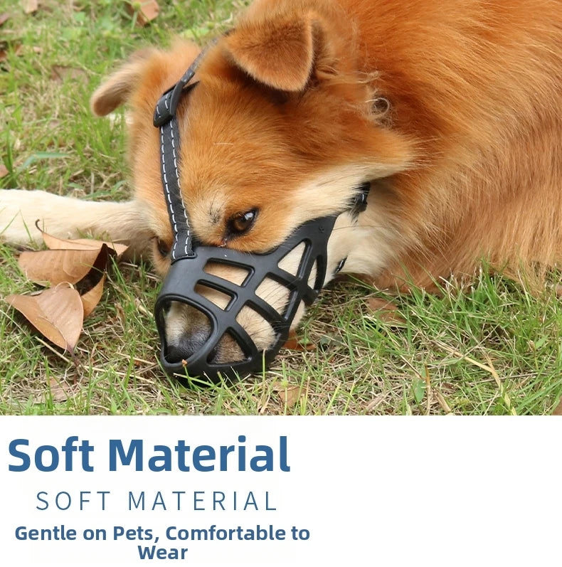 An orange dog wearing a black soft material muzzle while lying on green grass.