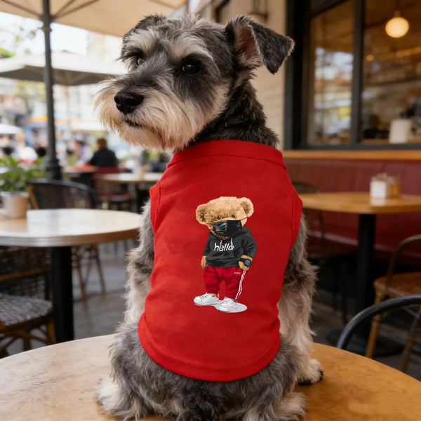 A gray dog wearing a red printed vest featuring a black silhouette of a bear face.