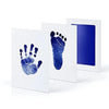 White framed art showing blue handprint and footprint impressions on paper
