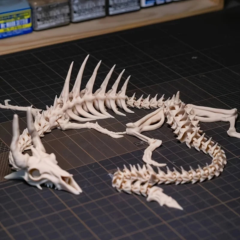 A white articulated dragon skeleton model displayed on a dark cutting mat.