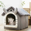 A gray pet house with a pitched roof and an arched entrance, featuring a white fluffy dog inside.