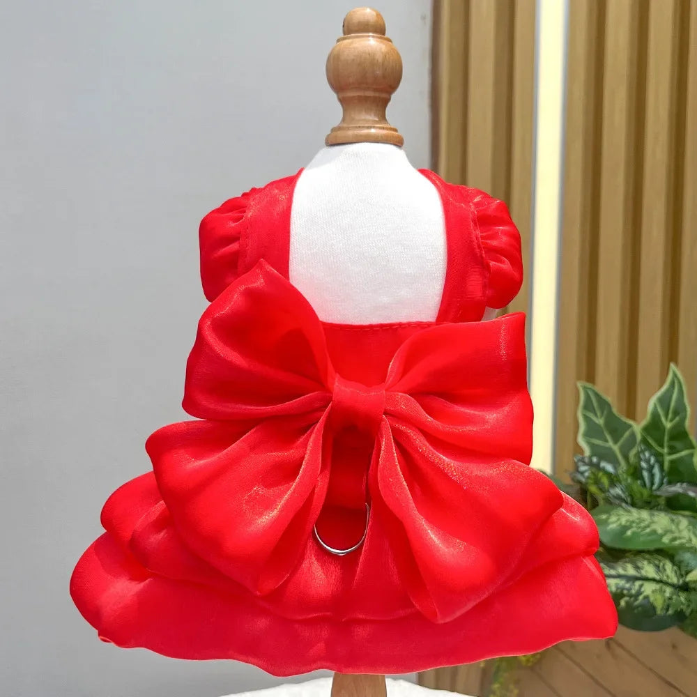 A bright red solid color pet dress with a large bow and D-ring for a small dog