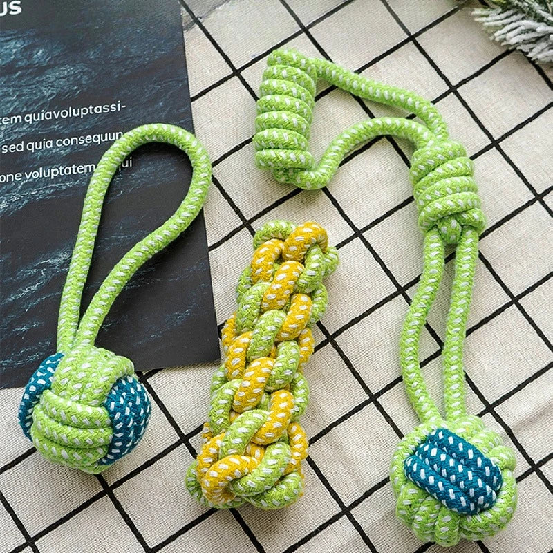 A green rope toy with blue accents is shown coiled and looped on a checkered surface.
