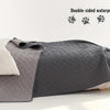 A gray double-sided waterproof dog mat is shown folded next to a light-colored pillow.