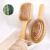 A wooden hair brush with natural bamboo bristles is shown next to a light pink exfoliating sponge.