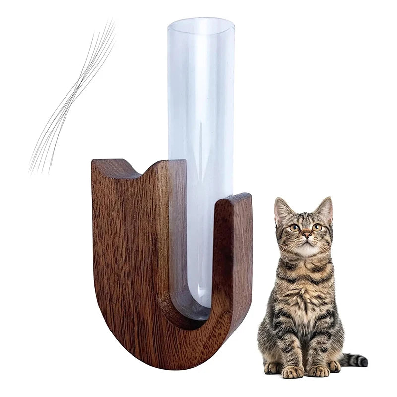 A wooden pet whisker collector vase with a clear glass tube and a tabby cat sitting beside it.