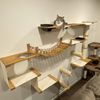 Wall-mounted cat climbing shelves featuring a wooden hammock and scratching post on a white wall.
