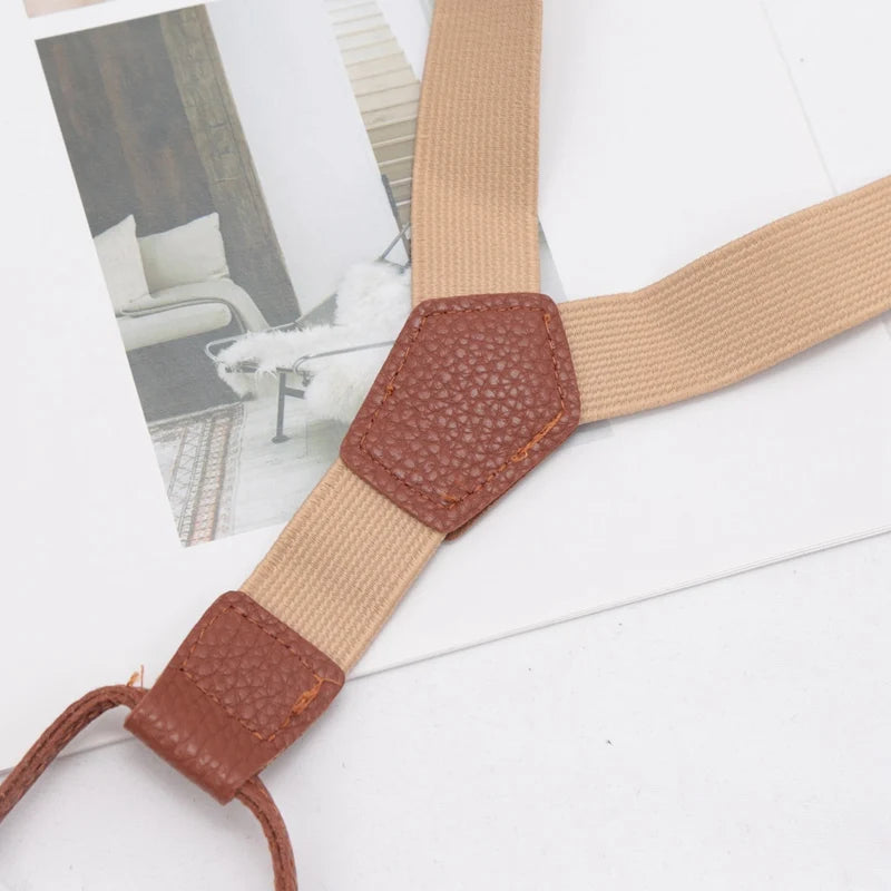 A pair of tan and brown adjustable clip-on suspenders for kids displayed on a white background.