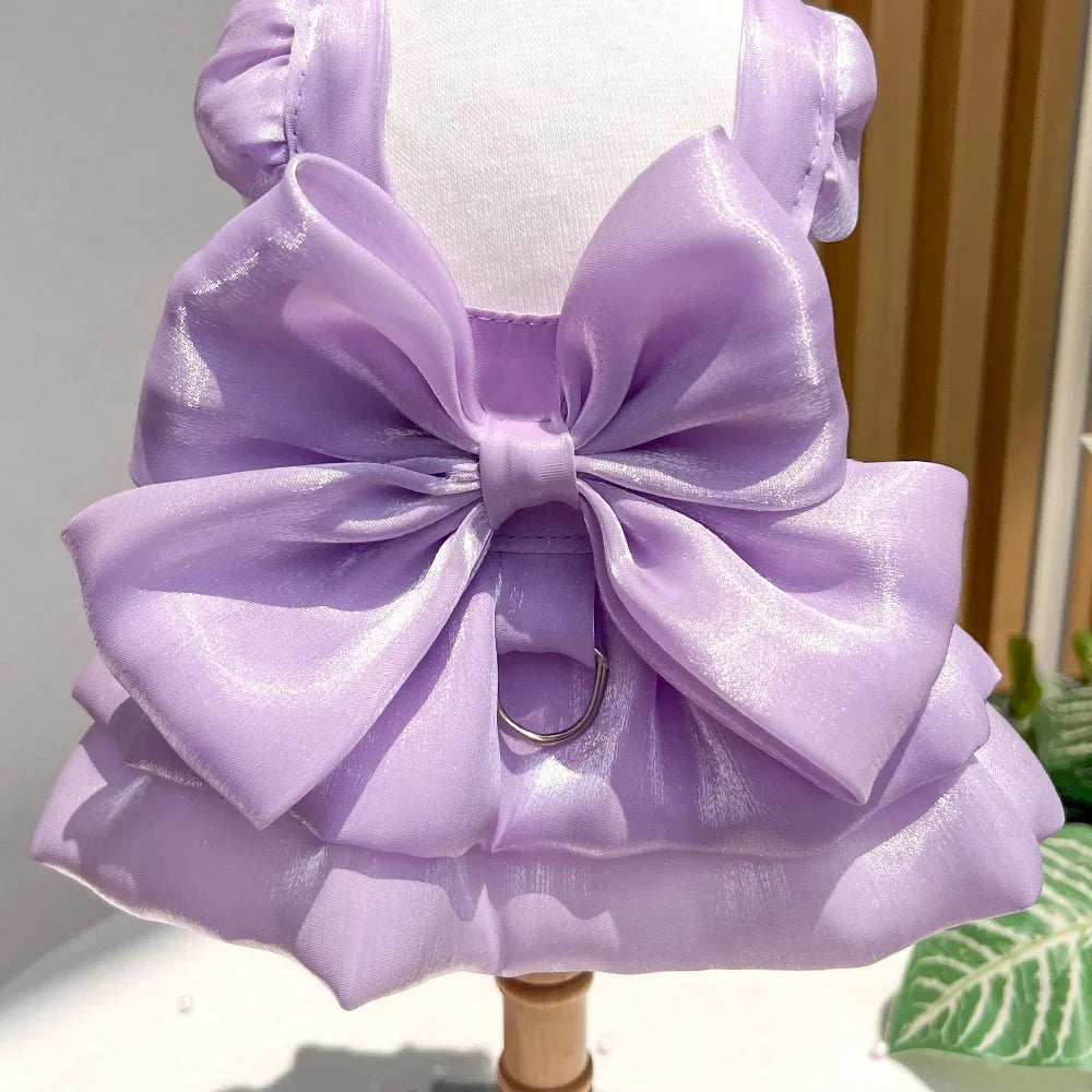 A lavender satin pet dress with a large bow and D-ring for a small dog displayed on a mannequin.
