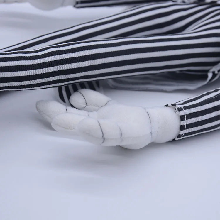 A close-up of a cartoon skeleton dog plush toy with white paws and black and white striped fabric.