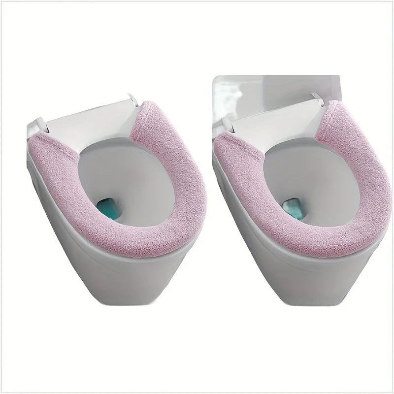 A pair of plush pink non-slip toilet seat covers shown from the front.