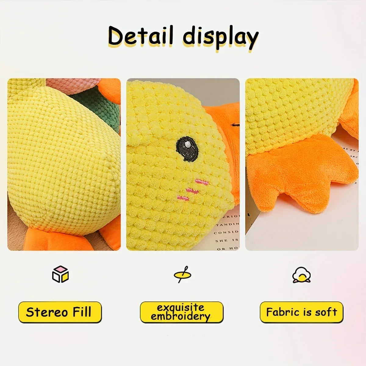 Detail display of a yellow embroidered duck plush toy with orange accents showing its texture and stitching.