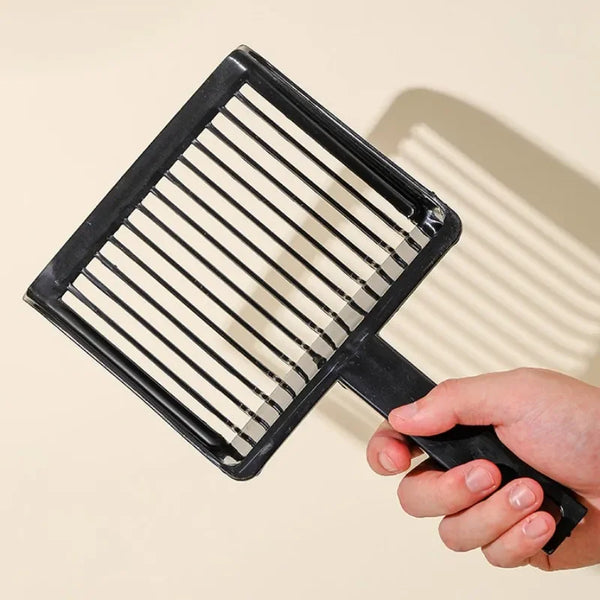 A black plastic cat litter scoop with a hanging hook is held by a hand.