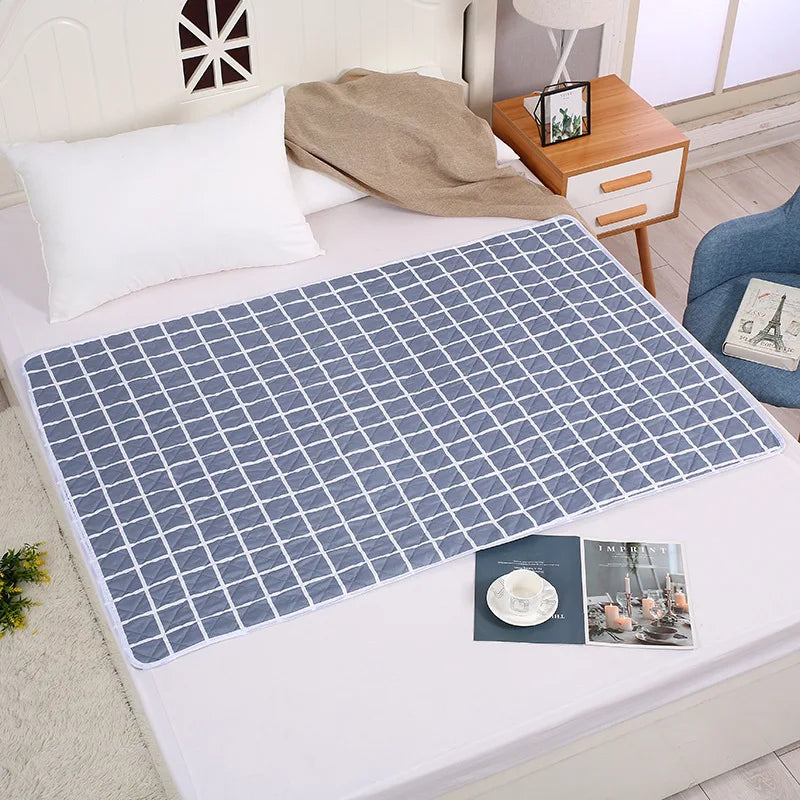 A blue diamond patterned waterproof bed protector pad is laid on a white bed sheet.