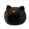 A black plush cat cave bed with ear shapes and a small orange tag.