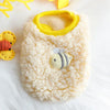 A fluffy cream velvet pet sweater with a yellow lining and a small bee appliqué resting on white fur.