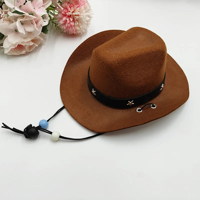 A brown felt cowboy hat with a black band and leather cord, resting on a white surface next to pink flowers.