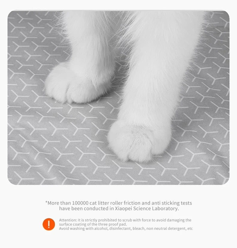 A close-up view of a white cat paw resting on a gray litter mat surface.