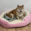 Ein hellbrauner Hund ruht in einem rosa, flauschigen Baumwollhundbett auf einem Holzfußboden.