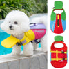 A white dog wearing a yellow life jacket for outdoor training, next to a red and green life jacket.