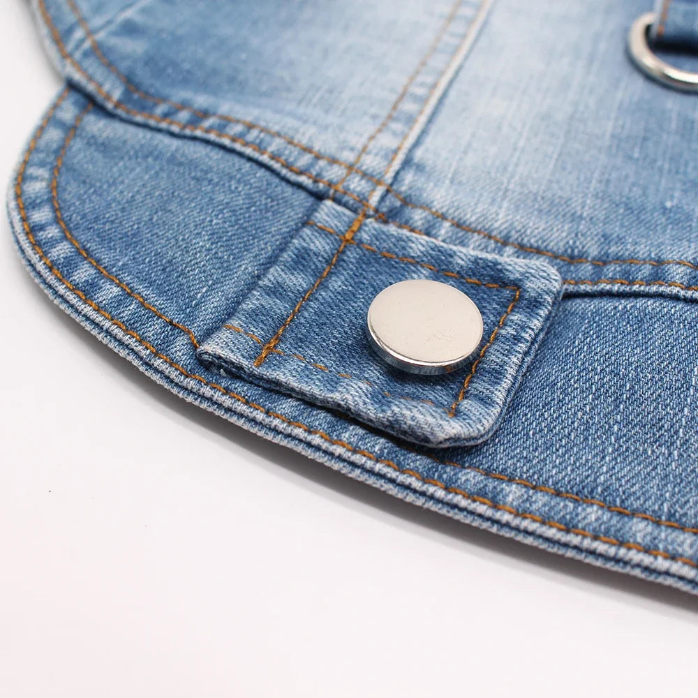 Close-up of a classic blue denim dog jacket showing a metal button detail on the fabric.