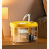 Fontaine à eau automatique jaune avec un bol en verre sur une surface en bois.