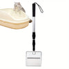 A stainless steel poop scooper with a long handle and a rectangular scraping end is shown next to a cat litter box.