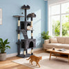 A multi-level gray cat tree with scratching posts and anti-tip kit stands in a bright living room next to a window.