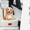 A fluffy golden dog is sitting comfortably in a light-colored pet car seat inside a vehicle.