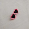Two pink heart-shaped pet hair clips with black centers resting on a white surface.