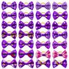 A collection of purple and pink pet hair bows with yellow rubber bands.