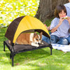 A portable elevated dog cot with a brown and yellow shade canopy is set up on the grass.