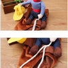 A stuffed dog costume jacket with a cowboy theme is shown lying on a wooden surface.