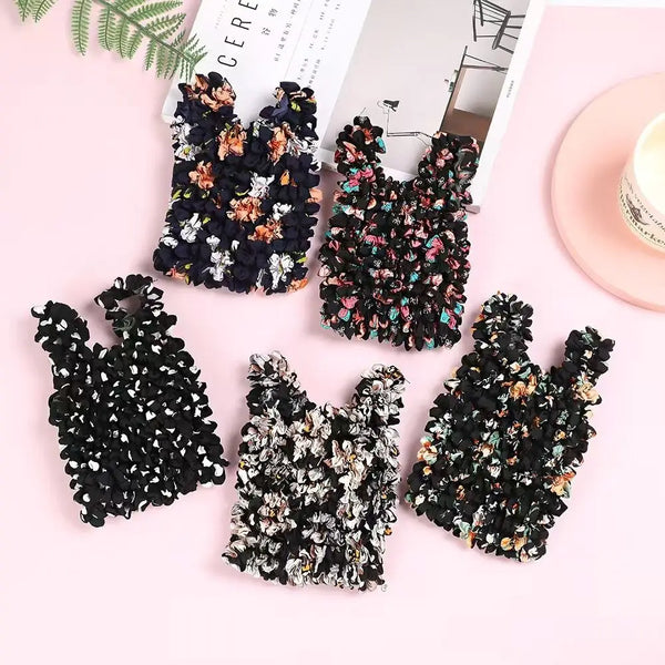 A collection of black floral fabric items, including a reusable foldable bubble shopping bag.