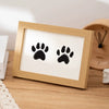 A wooden photo frame displaying two black paw prints on a white background.